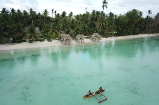 Fishers coming home on a paddle canoe after fishing on the fore reefs of Abaiang, Kiribati