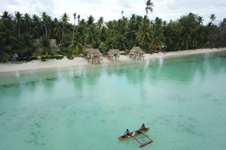 Fishers coming home on a paddle canoe after fishing on the fore reefs of Abaiang, Kiribati